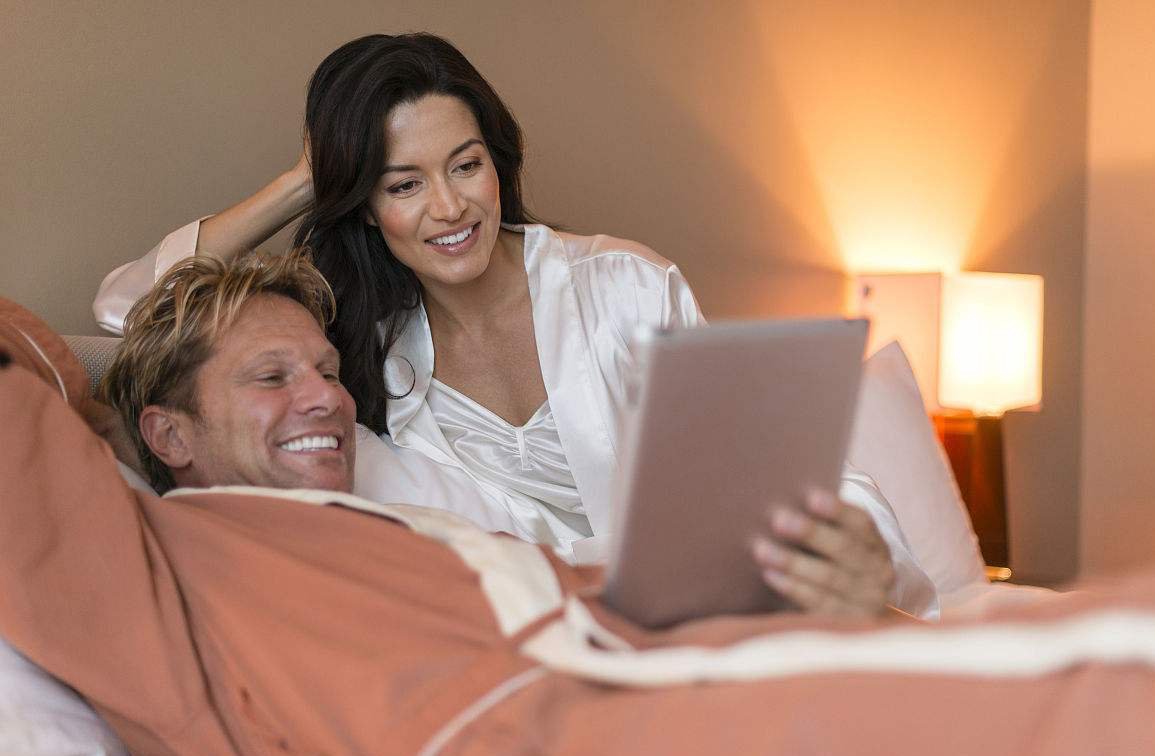 Couple in hotel room looking at computer