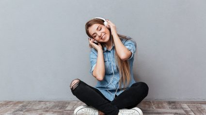 woman sitting on floor listening and enjoying music on headphones