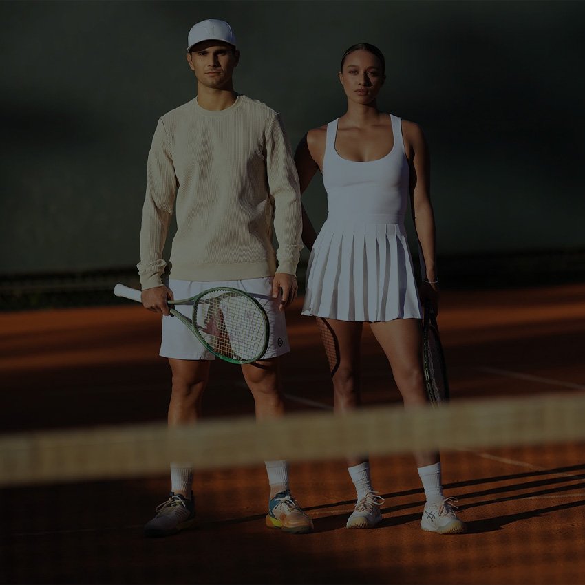 A man and woman modeling stylish tennis outfits on a tennis court